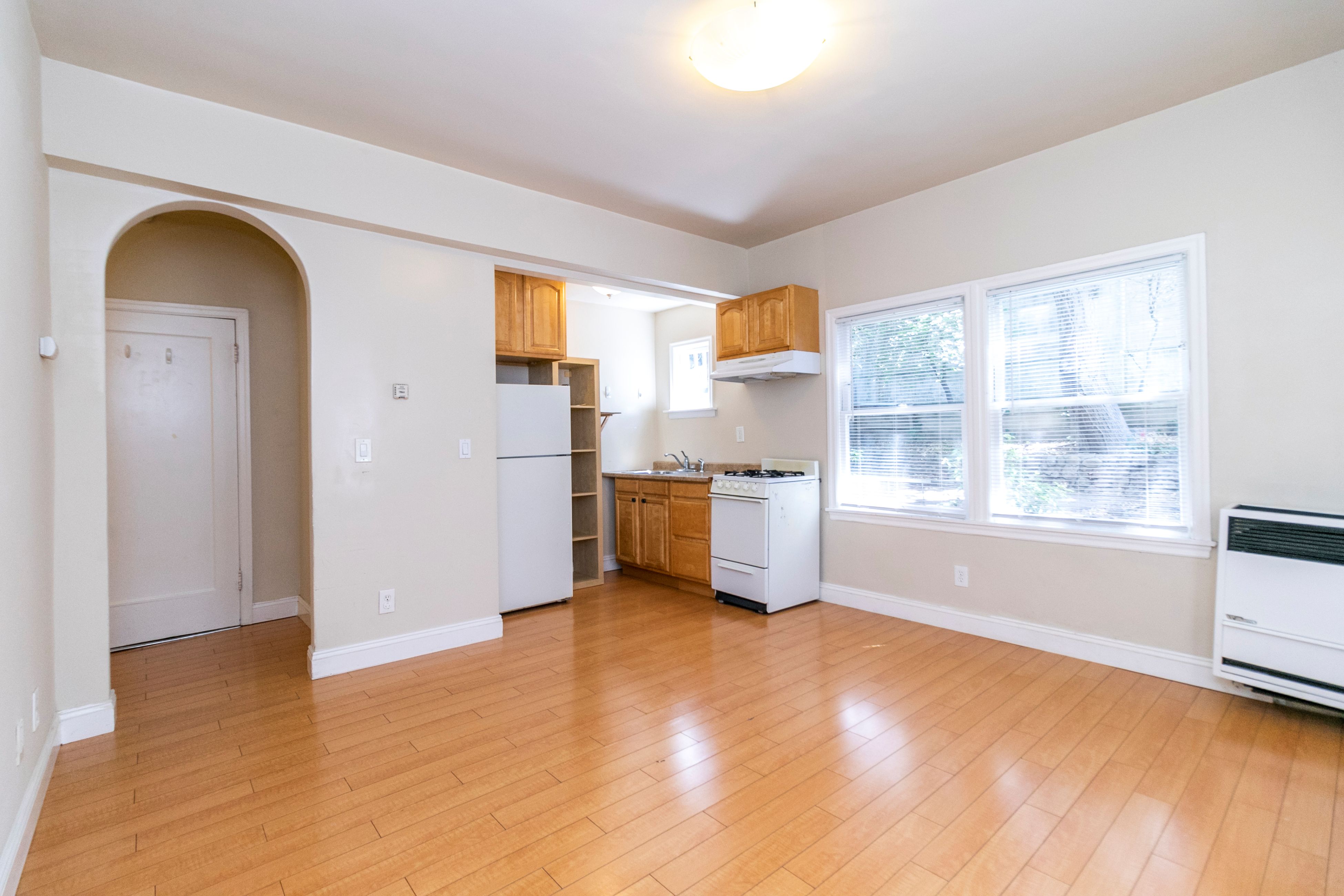 A kitchen with white appliances and wooden floors.